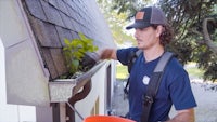 a man cleaning the gutters of a house