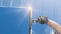 a man cleaning a window with a blue sky